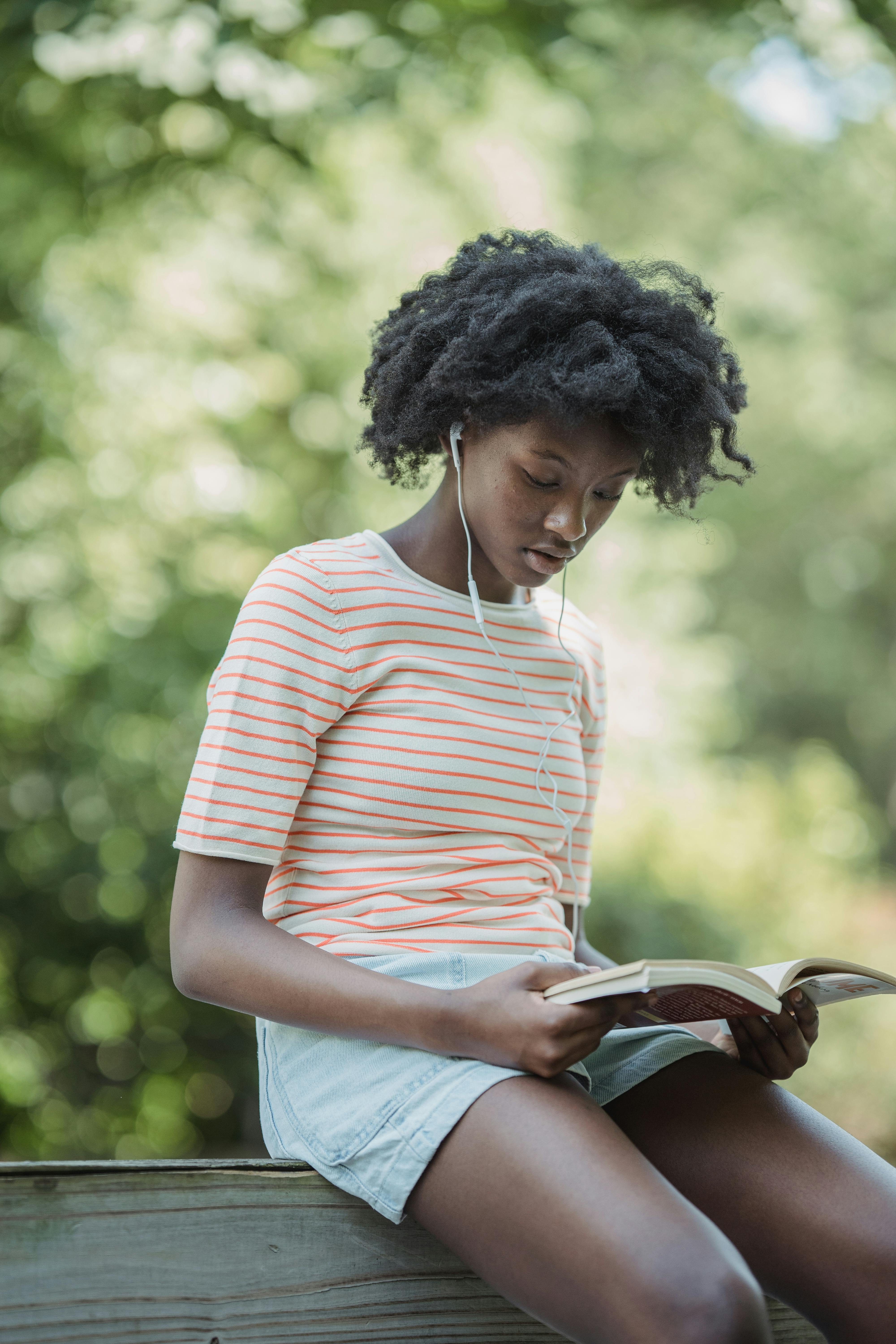 Teen girl in a striped t-shirt and shorts reading a book
